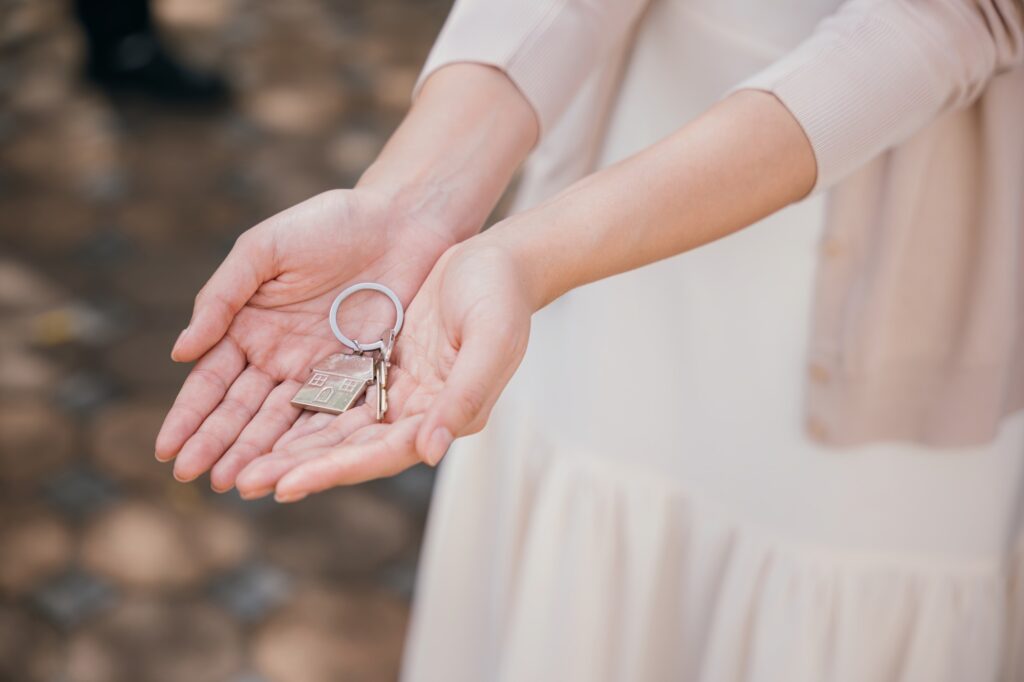 Landlord's hand offers keys for a new home symbolizing investment and tenant happiness. Real estate